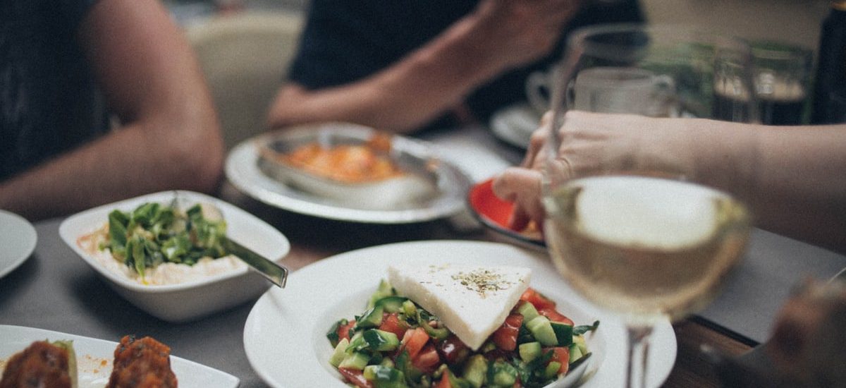 A beautifully arranged dinner setting featuring fresh salad and white wine, perfect for a fine dining experience.