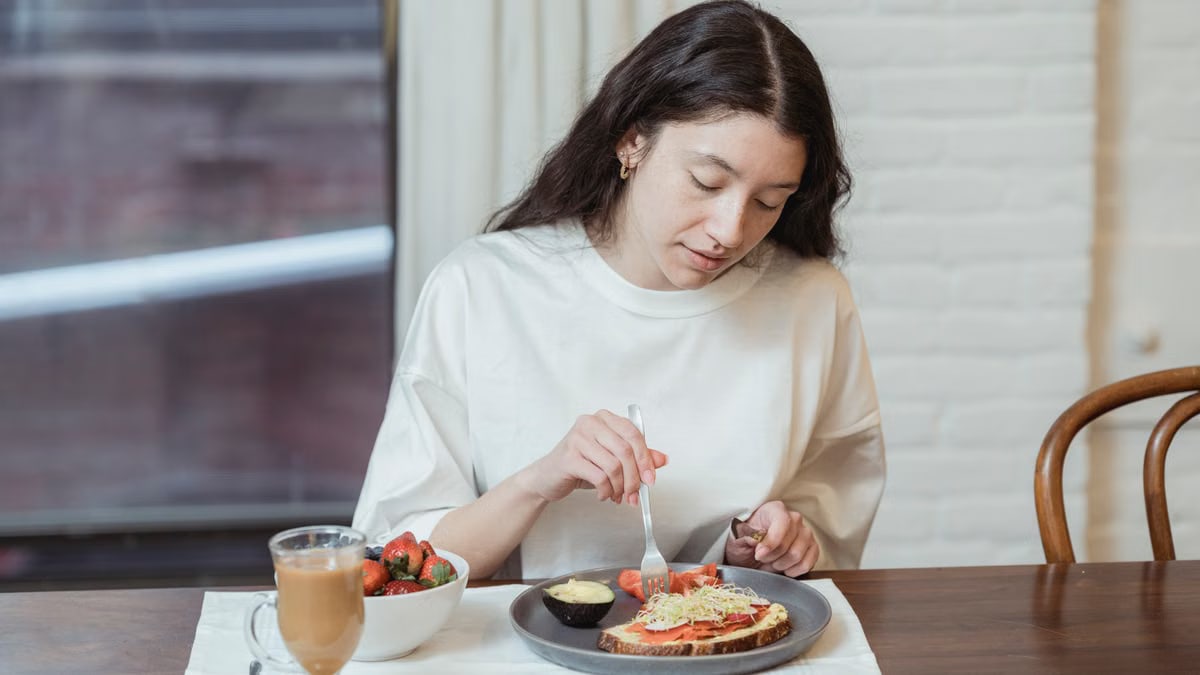 Woman having a nutritious breakfast with toast and strawberries in a cozy indoor setting.