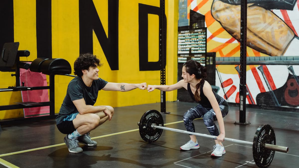 Man and woman in gym sharing a fist bump to celebrate a workout session.